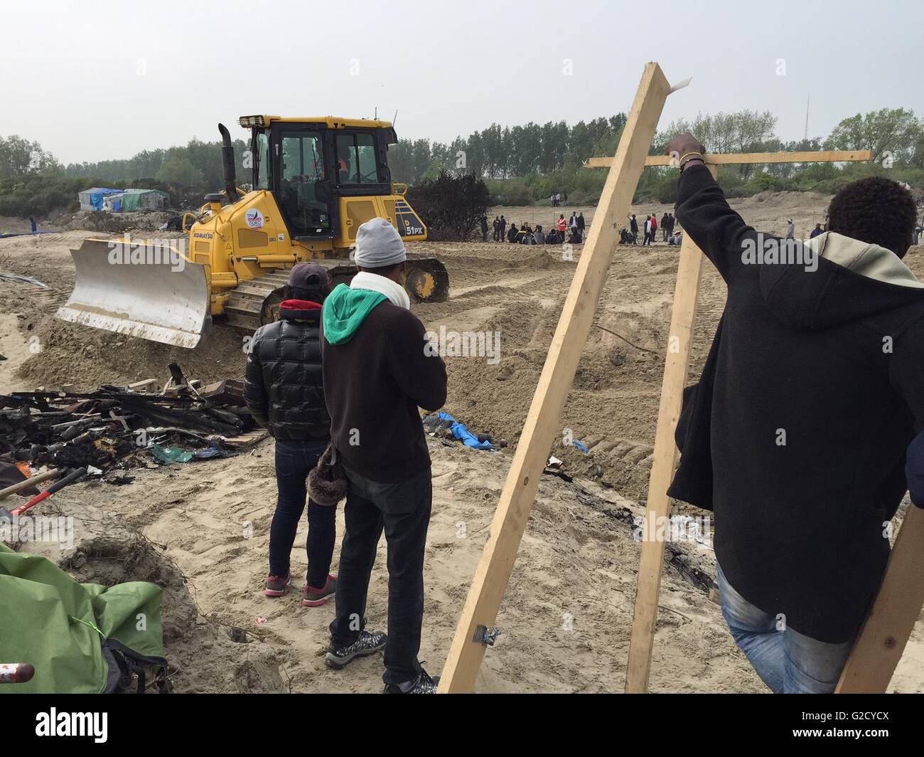 Calais, Francia. 27 Maggio, 2016. I rifugiati di guardare un bulldozer la guida sul sito del campo migrante soprannominato "Jungle' nella periferia di Calais, Francia, 27 maggio 2016. Quaranta persone sono rimaste ferite in una rissa al campo profughi, le autorità locali ha detto. Diversi rifugi sono stati bruciati. Foto: Anna Psaroudakis/dpa/Alamy Live News Foto Stock