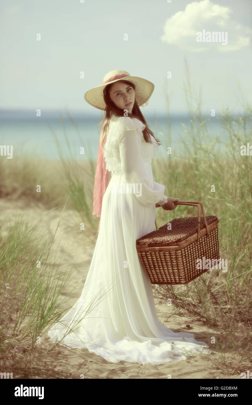 Donna in spiaggia con cesto per pic-nic Foto Stock