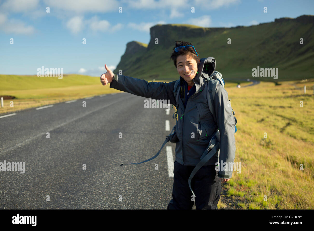 Sorridente Giovane autostop lungo la strada rurale Foto Stock