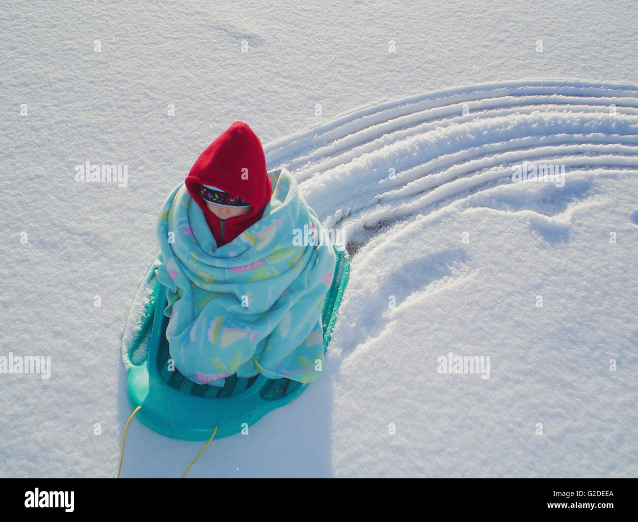 Bambino avvolto in un lenzuolo sul Sled nella neve Foto Stock