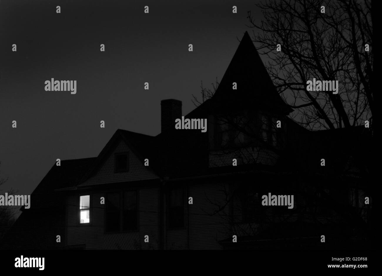 Vecchia casa di notte con una finestra illuminata Foto Stock