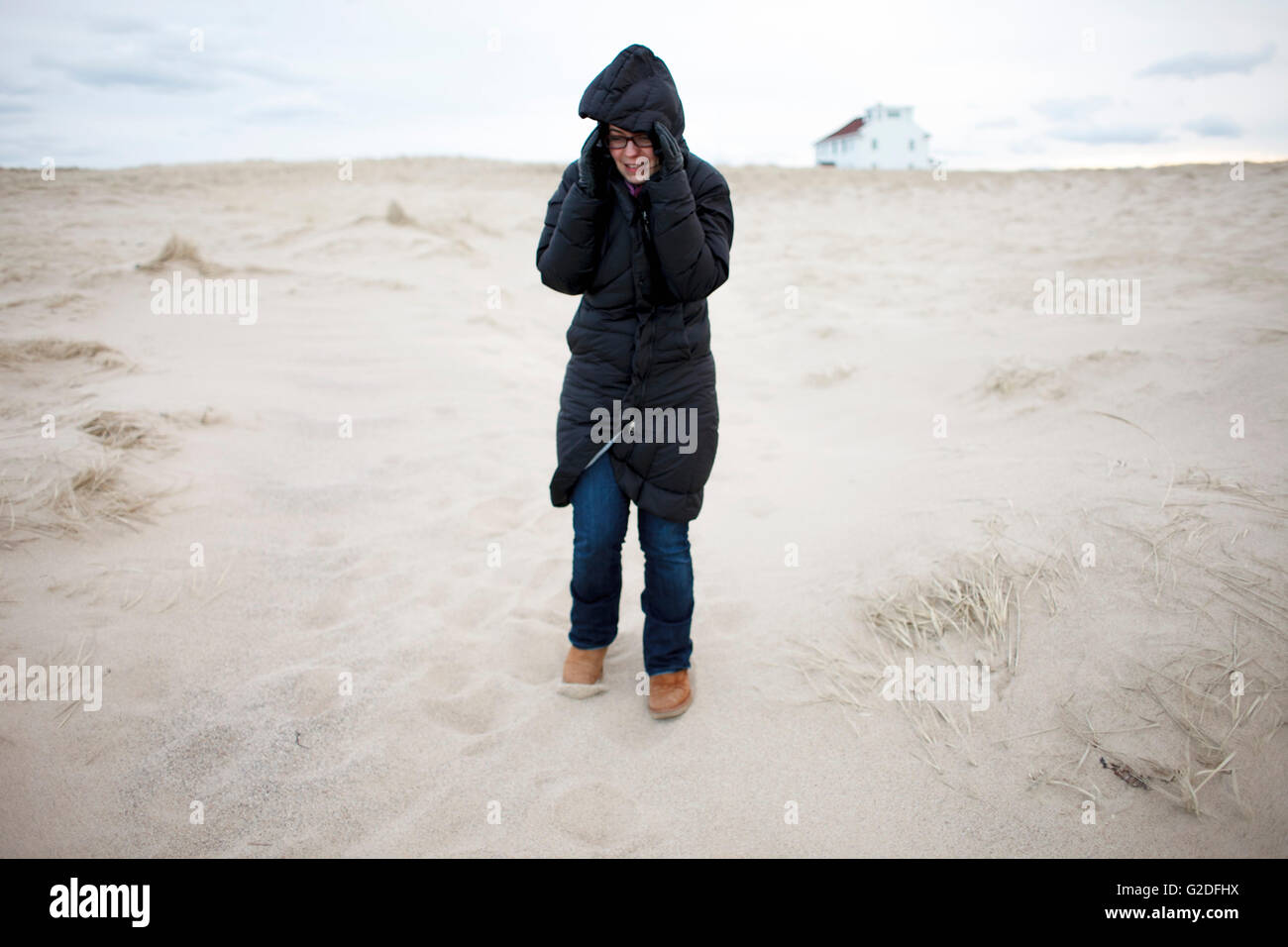 Giovane donna adulta in cappotto camminando sulla spiaggia Foto Stock