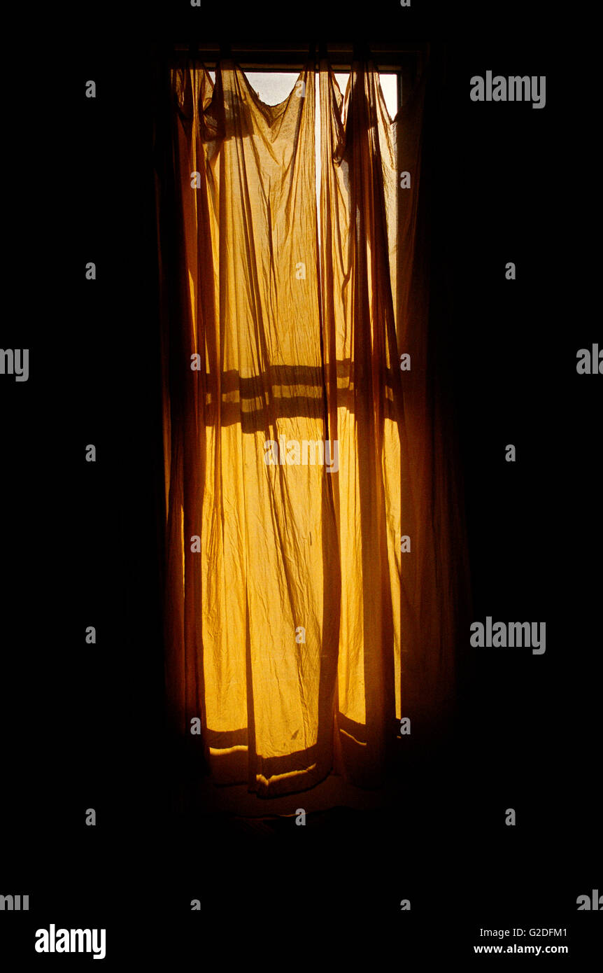 La tendina gialla sulla finestra in camera oscura Foto Stock