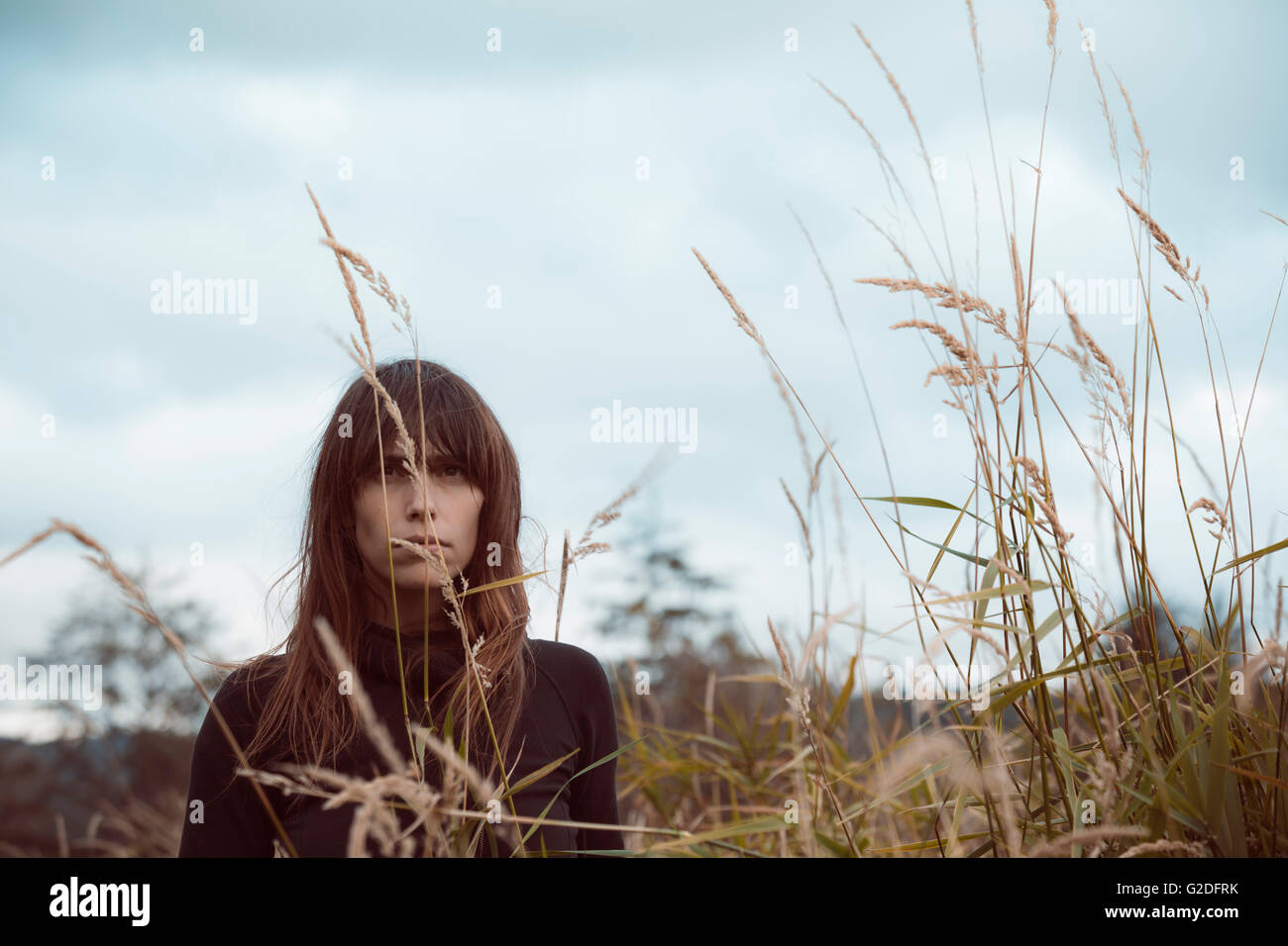 Giovane donna adulta in piedi nel campo di grano Foto Stock