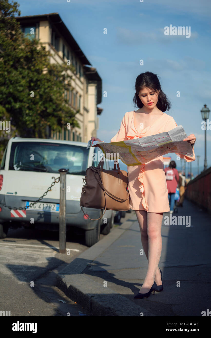 Giovane donna che guarda su una mappa turistica ricerca per la direzione di Firenze Italia Foto Stock