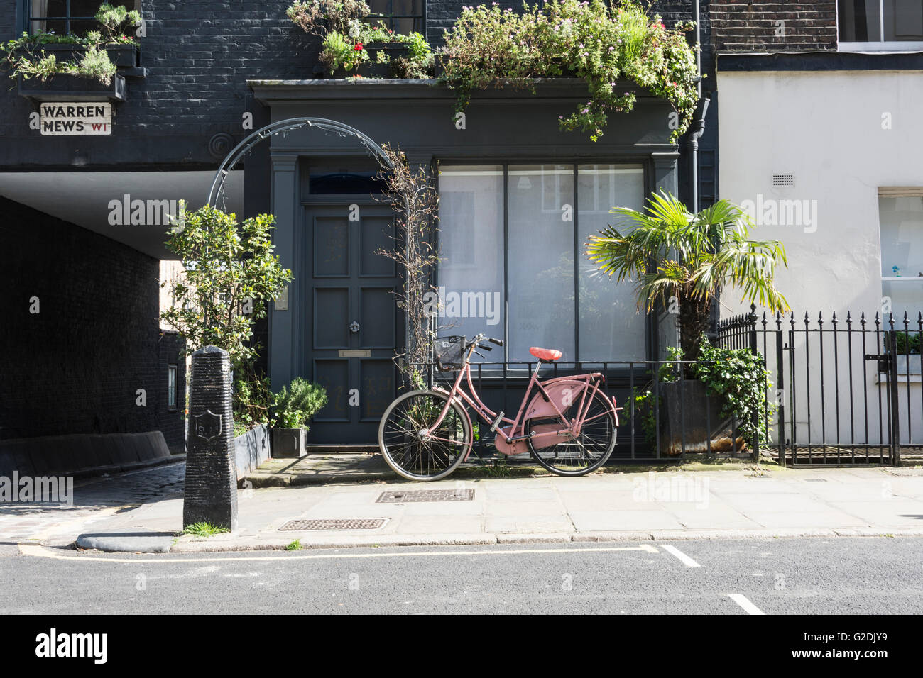 Un classico stile pink ladies bicicletta parcheggiata al di fuori di una pittoresca casa su Warren Mews a Fitzrovia, London, Regno Unito Foto Stock