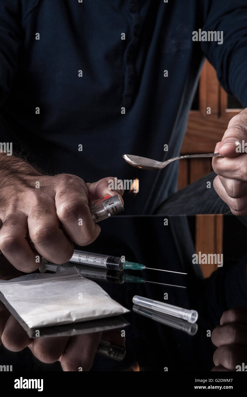 Preparazione di farmaci sul cucchiaino di un accendino su sfondo scuro con la riflessione Foto Stock