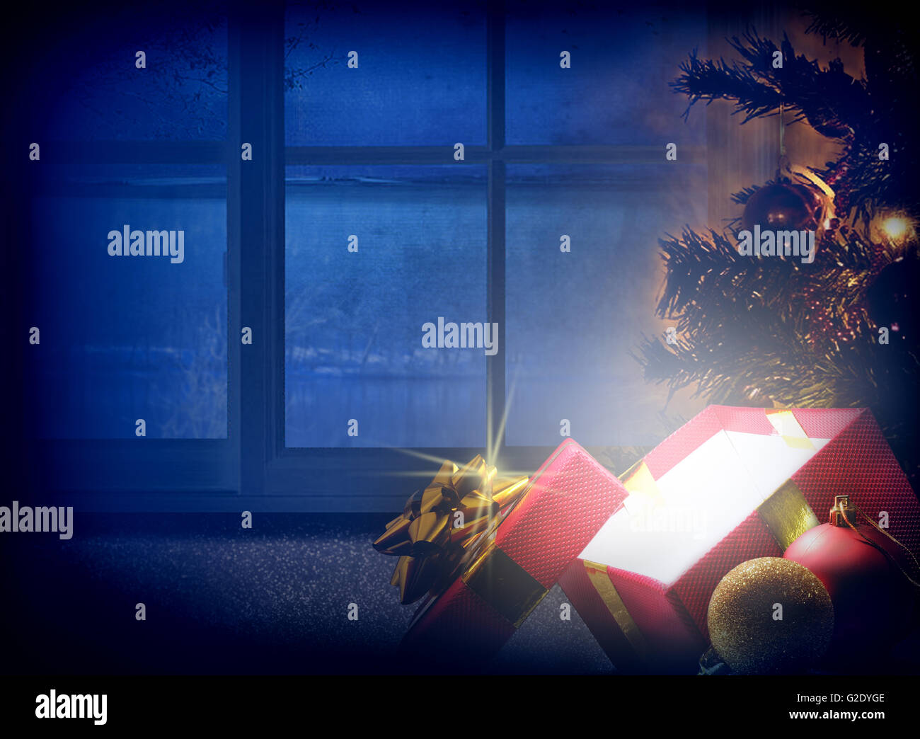 Composizione di Natale alla vigilia di Natale. Candela di dono, albero e palle di decorazione con lo sfondo della finestra. Tonalità bluastra sogno. Foto Stock