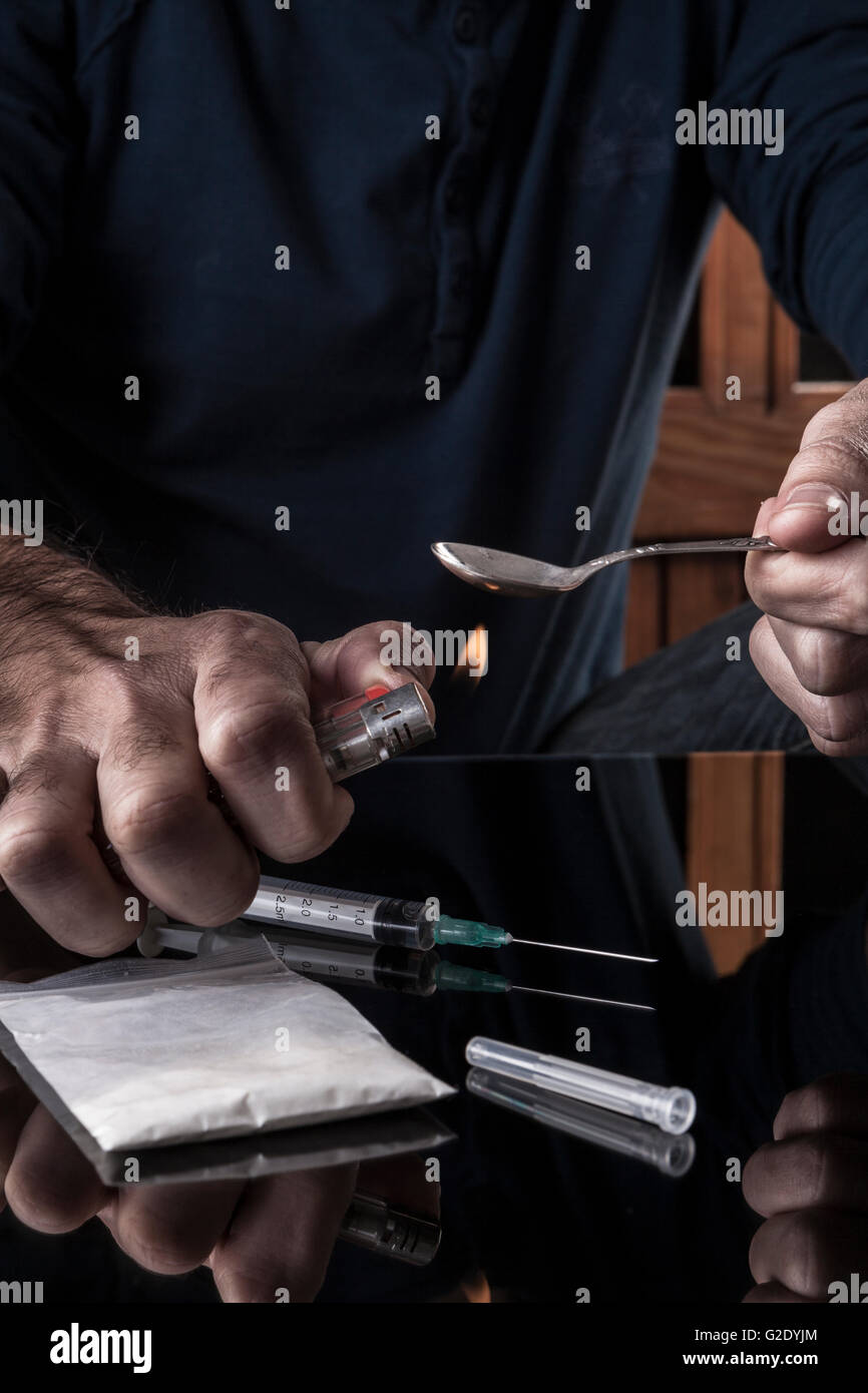 Preparazione di farmaci sul cucchiaino di un accendino su sfondo scuro con la riflessione Foto Stock