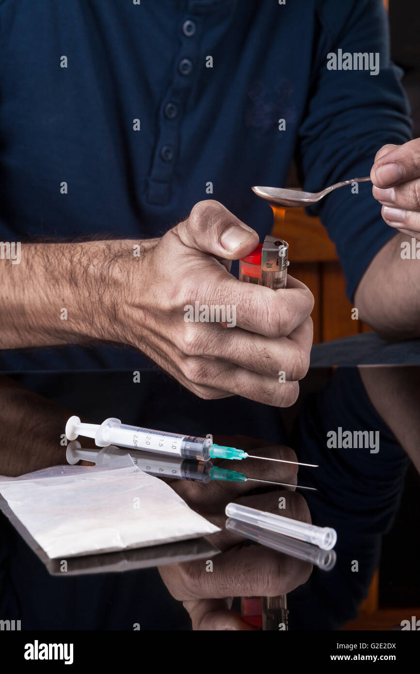 Preparazione di farmaci sul cucchiaino di un accendino su sfondo scuro con la riflessione Foto Stock
