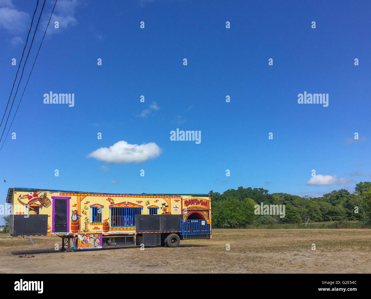 Trailer di carnevale in un vuoto molto con alberi in background e un luminoso cielo blu Foto Stock