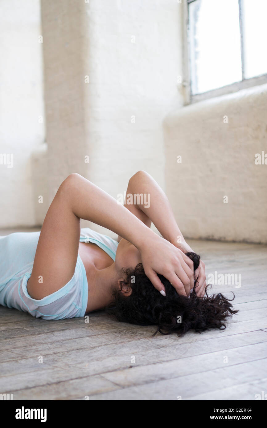 Giovane donna posa sul pavimento in testa le mani Foto Stock