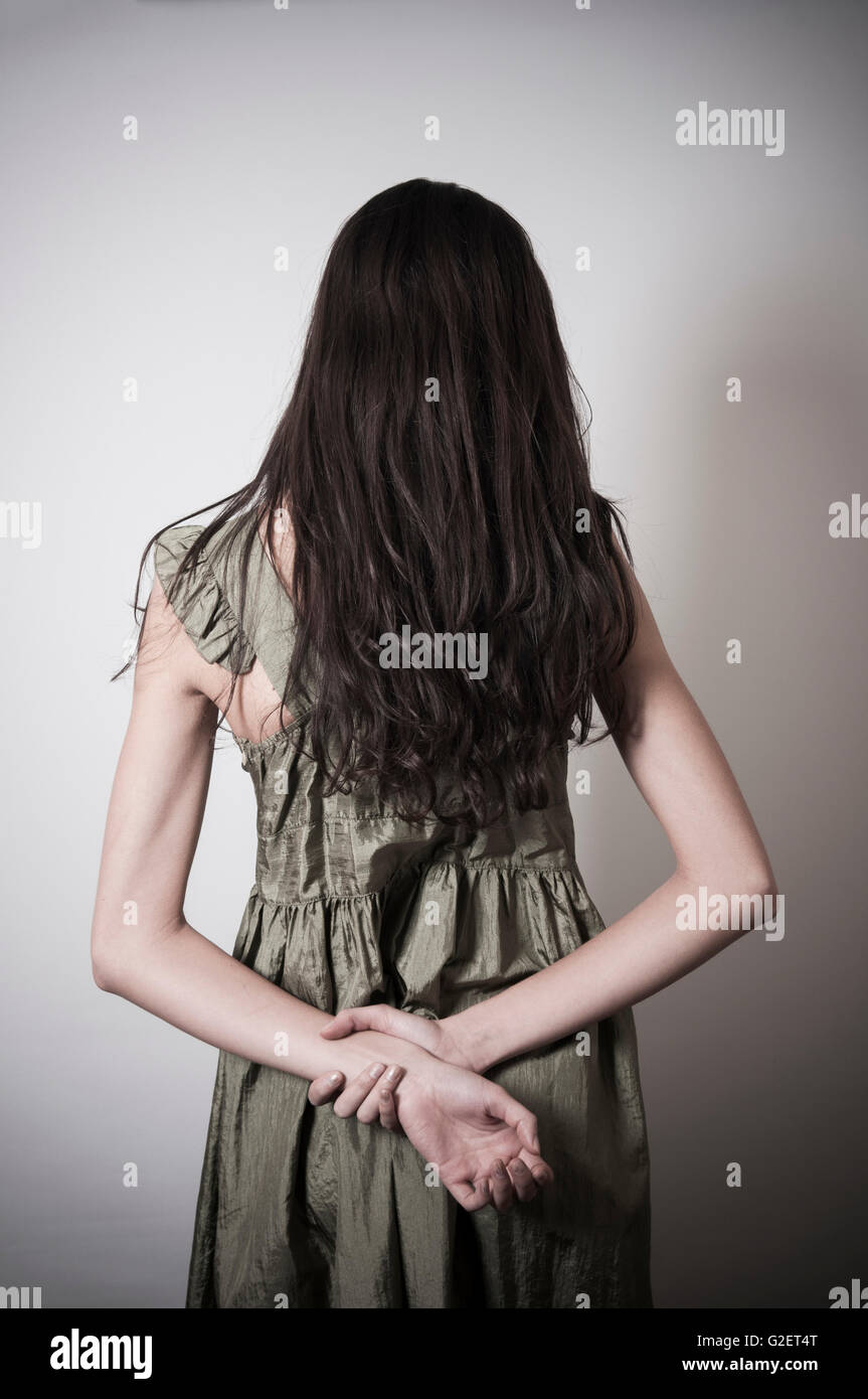 Vista posteriore di un triste snella donna in piedi con le mani dietro la schiena Foto Stock