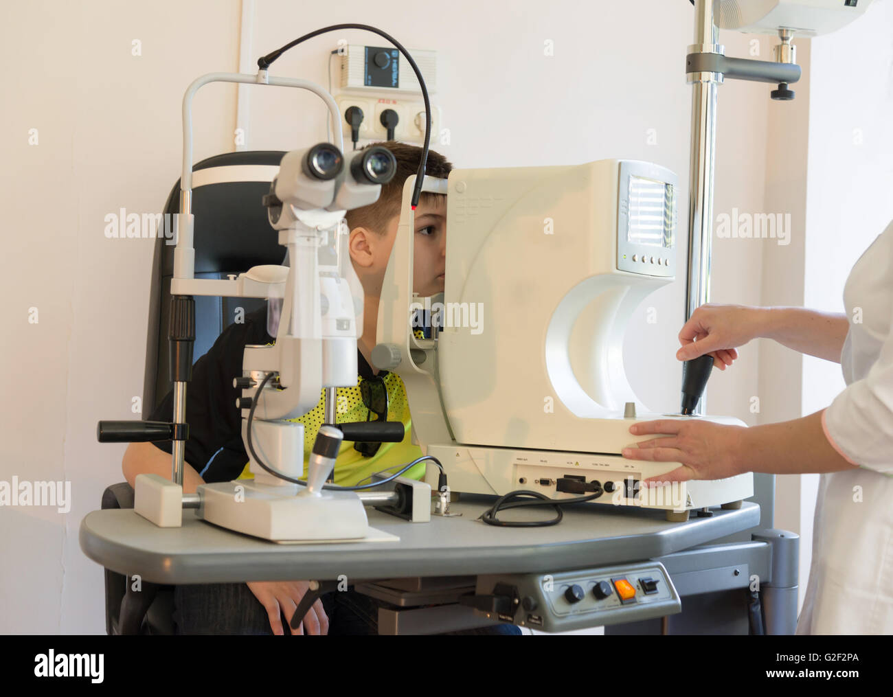 Il medico controlla il bambino gli occhi di fronte al dispositivo Foto Stock