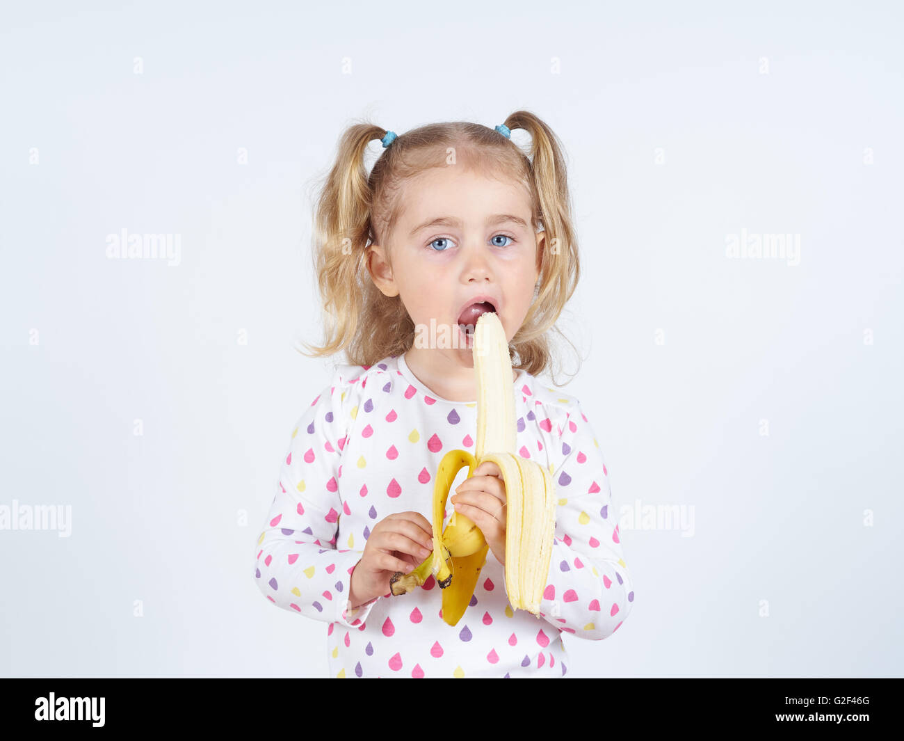 Bambina a mangiare una banana fresche. Mangiare sano. La dieta. Il vegetarianismo. Foto Stock