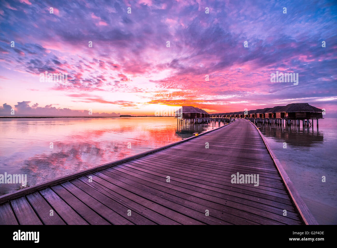 Incredibile sfondo astratto. Bel tramonto colori delle Maldive. Lungo pontile e lussuose ville overwater Foto Stock