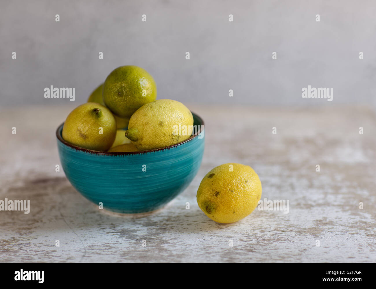 Limoni e limette in blu recipiente di ceramica sul tavolo Foto Stock