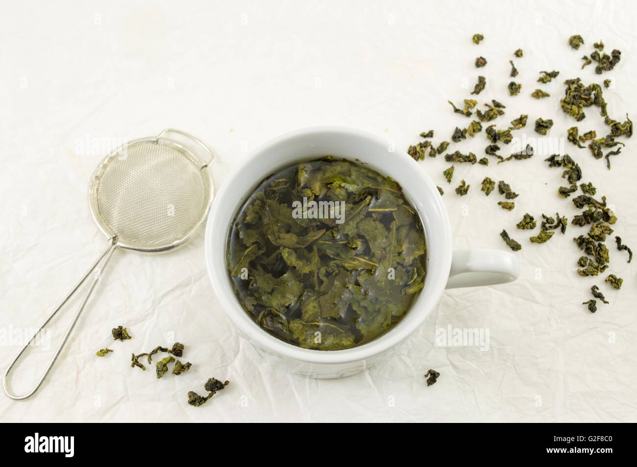 Il tè verde con foglia gelsomino in una tazza su tessuti di seta Foto Stock