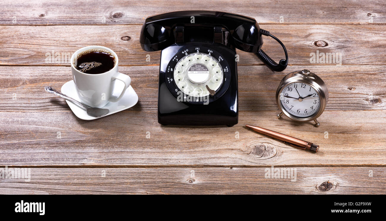Vintage desktop con antico telefono, penna, orologio e caffè su rustiche tavole in legno. Foto Stock