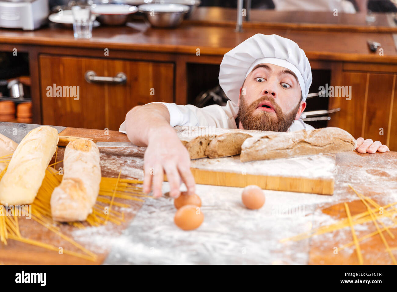 Carino divertente baker con la barba scherzando e divertendosi in cucina Foto Stock