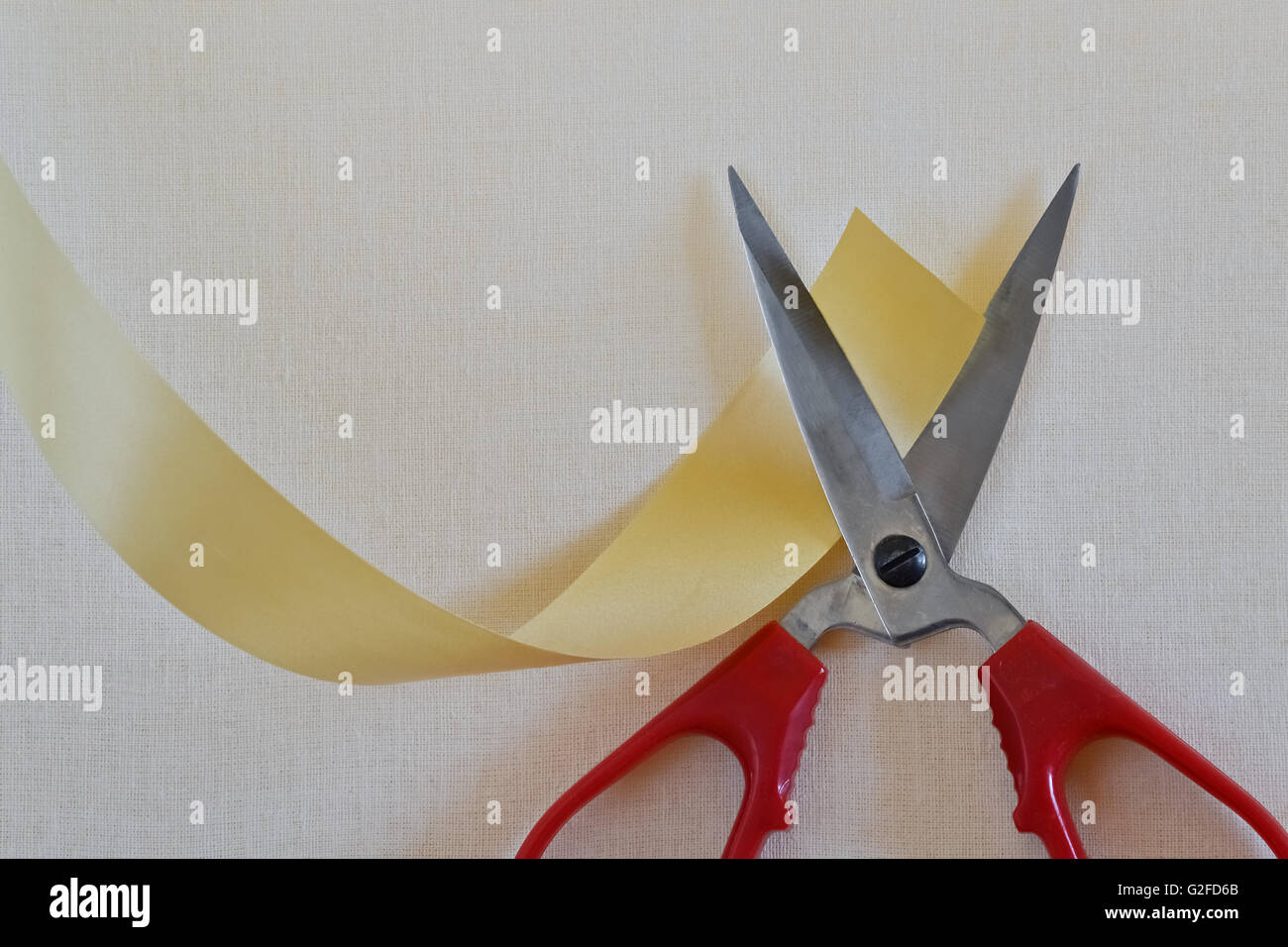 Primo piano di forbici e nastro giallo sul brillante background tessile Foto Stock