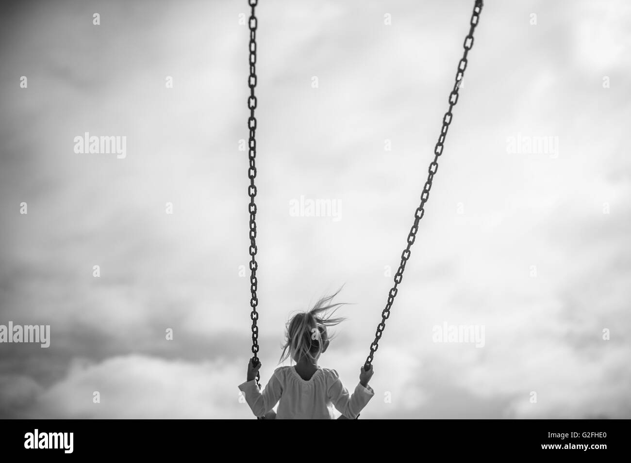 La ragazza sull'altalena contro il cielo grigio, vista posteriore Foto  stock - Alamy
