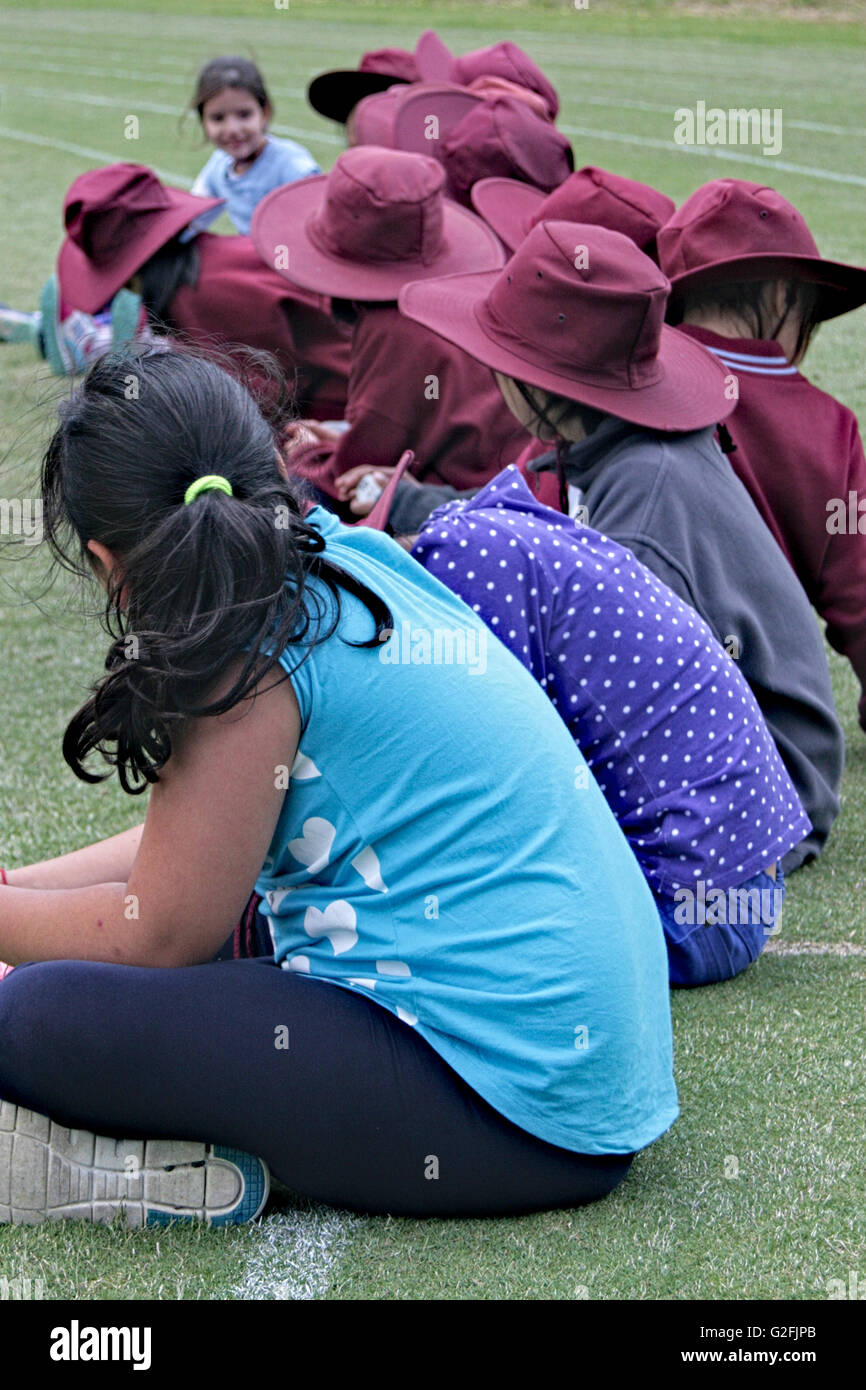 Riga della scuola i bambini con sunhats sulla seduta sull'erba. Foto Stock