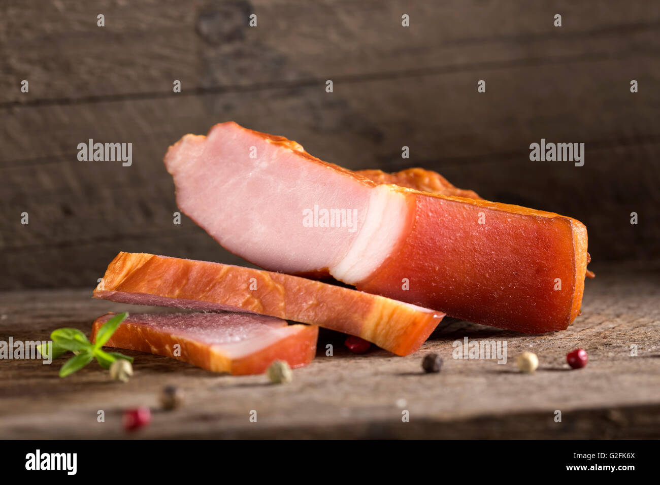 Close up di carne di maiale affumicata fette di filetto su un tavolo di legno con erbe aromatiche Foto Stock