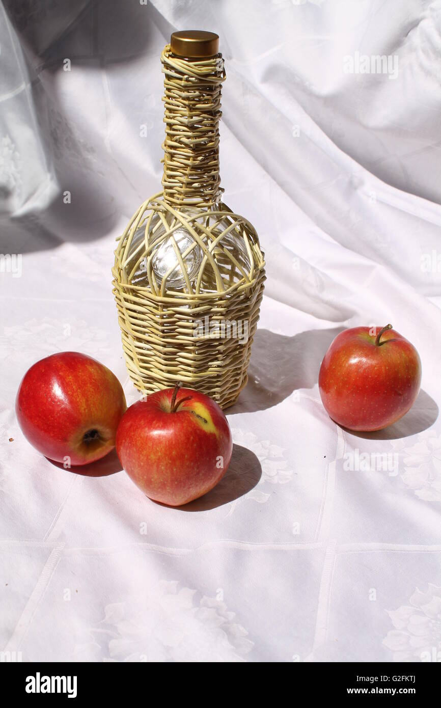 Bottiglia di vetro nella carcassa di armatura con tre rossi succose mele belle decorazioni per tempo di dessert Foto Stock