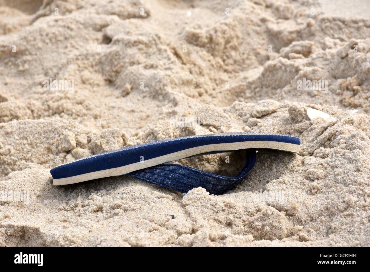 Un flip flop recante sulla spiaggia in sabbia Foto Stock