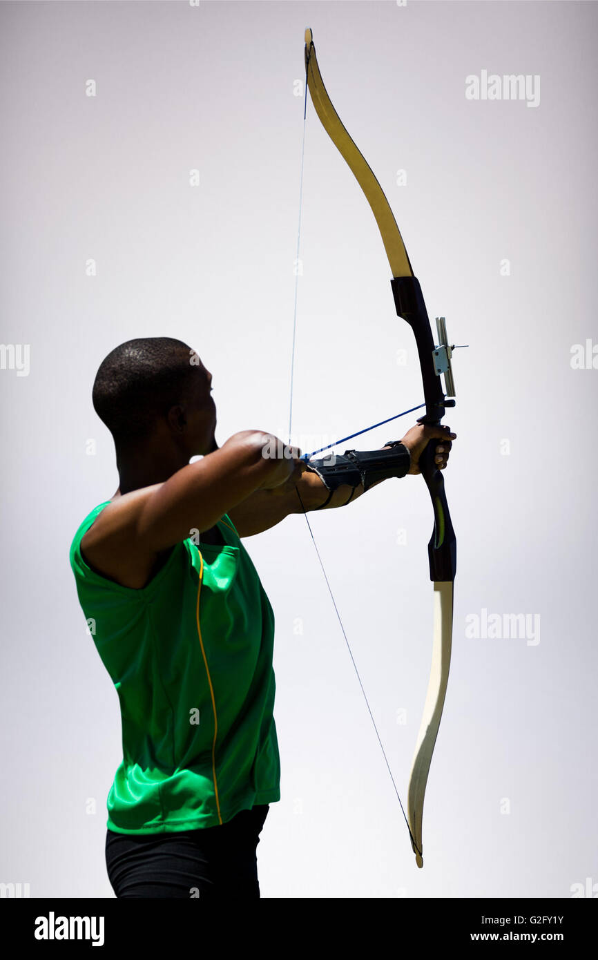 Immagine composita della vista posteriore di uno sportivo facendo tiro con l'arco su sfondo bianco Foto Stock