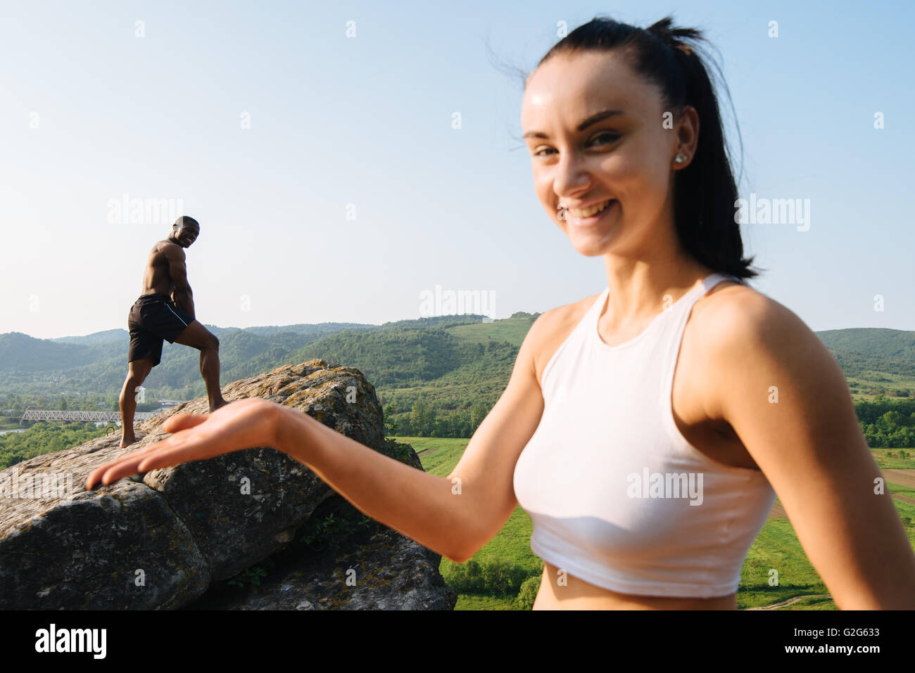 Sorridendo allegro razza mista paio di istruttori di yoga posa all'aperto nelle montagne rocciose. Foto Stock