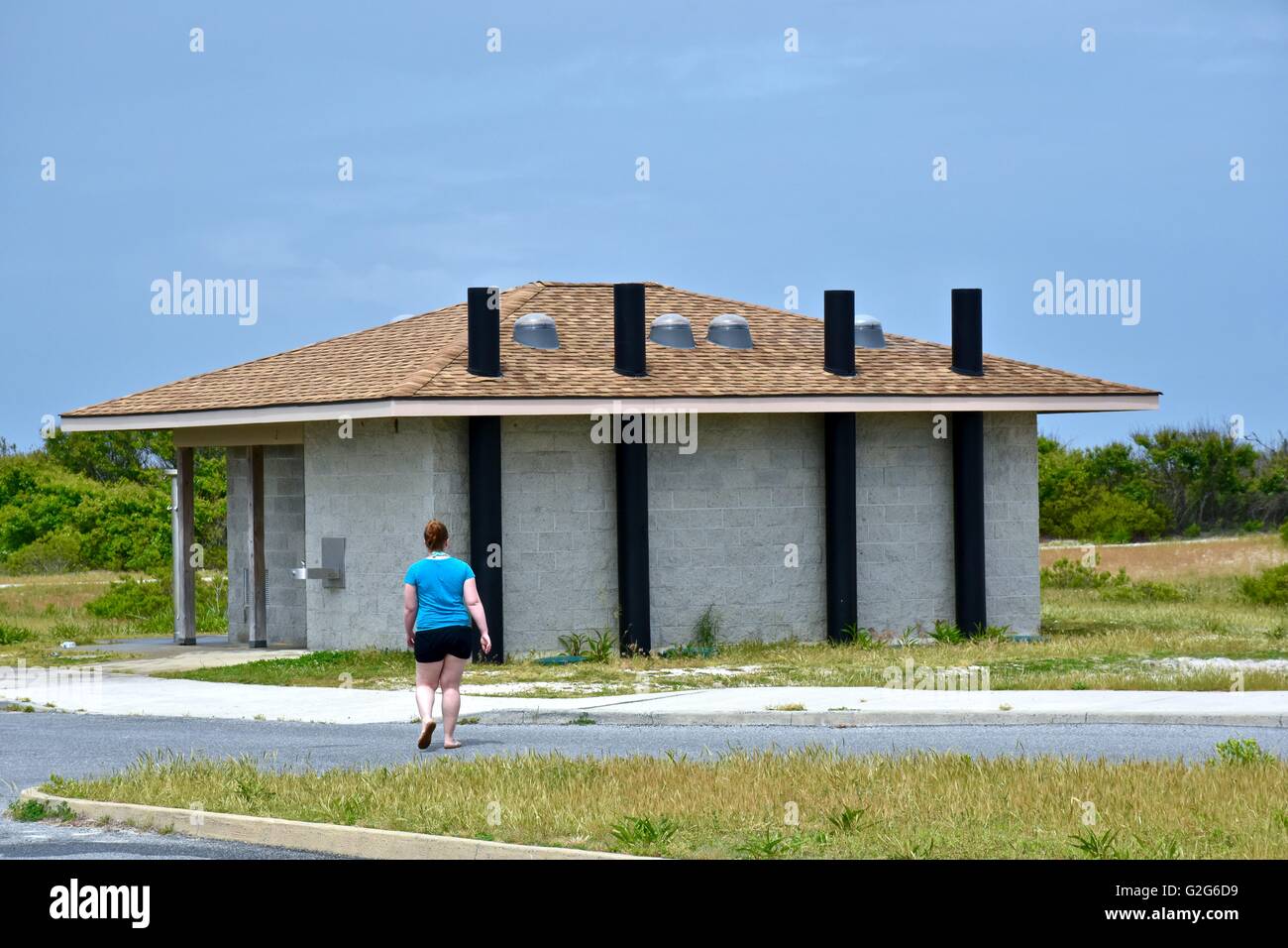 Una donna che cammina per il bagno struttura presso la spiaggia Foto Stock