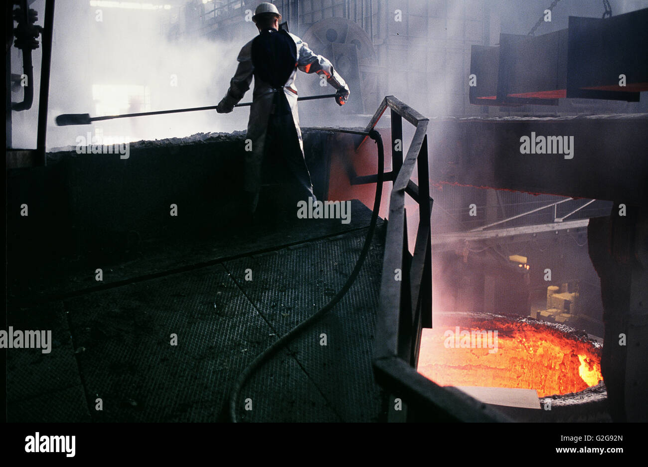 Germania - Velbert, Krupp la produzione di acciaio. Lavoratore che indossa indumenti protettivi opera vicino al forno con acciaio fuso Foto Stock