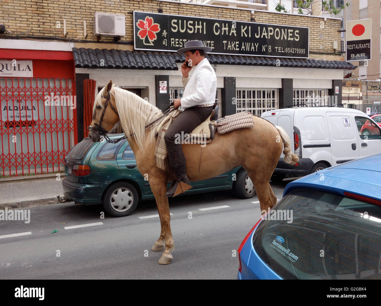 Siviglia Andalusia Spagna Feria di Abril uomo sul cavallo palomino tramite telefono cellulare al di fuori del ristorante di sushi Foto Stock