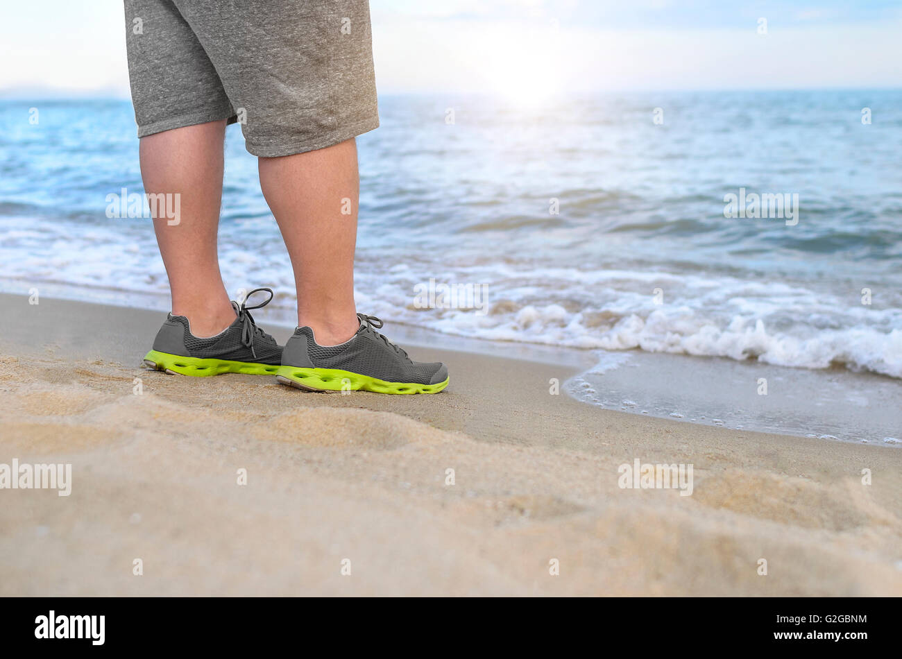 L uomo si trova sulla spiaggia. Piedi in scarpe da corsa closeup Foto stock  - Alamy