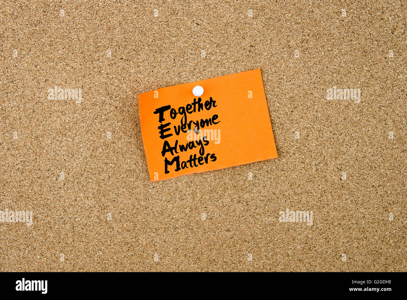 Acronimo di Business Team come insieme tutti conta sempre scritto su carta arancione nota appuntata sulla bacheca di sughero con il bianco thumbtacks, copia dello spazio disponibile Foto Stock