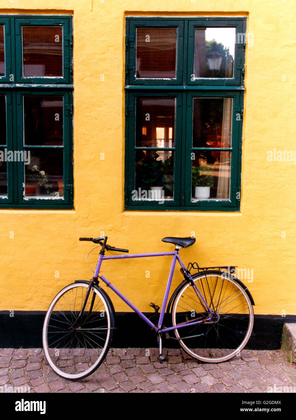 Bicicletta viola contro la parete Foto Stock