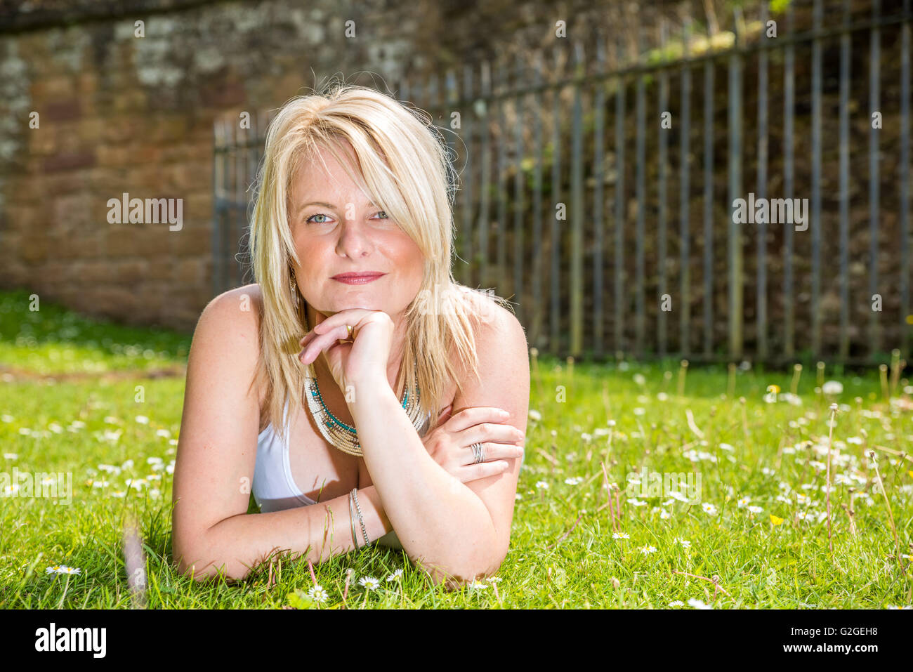 Una bionda femmina attraente giacente in erba Foto Stock