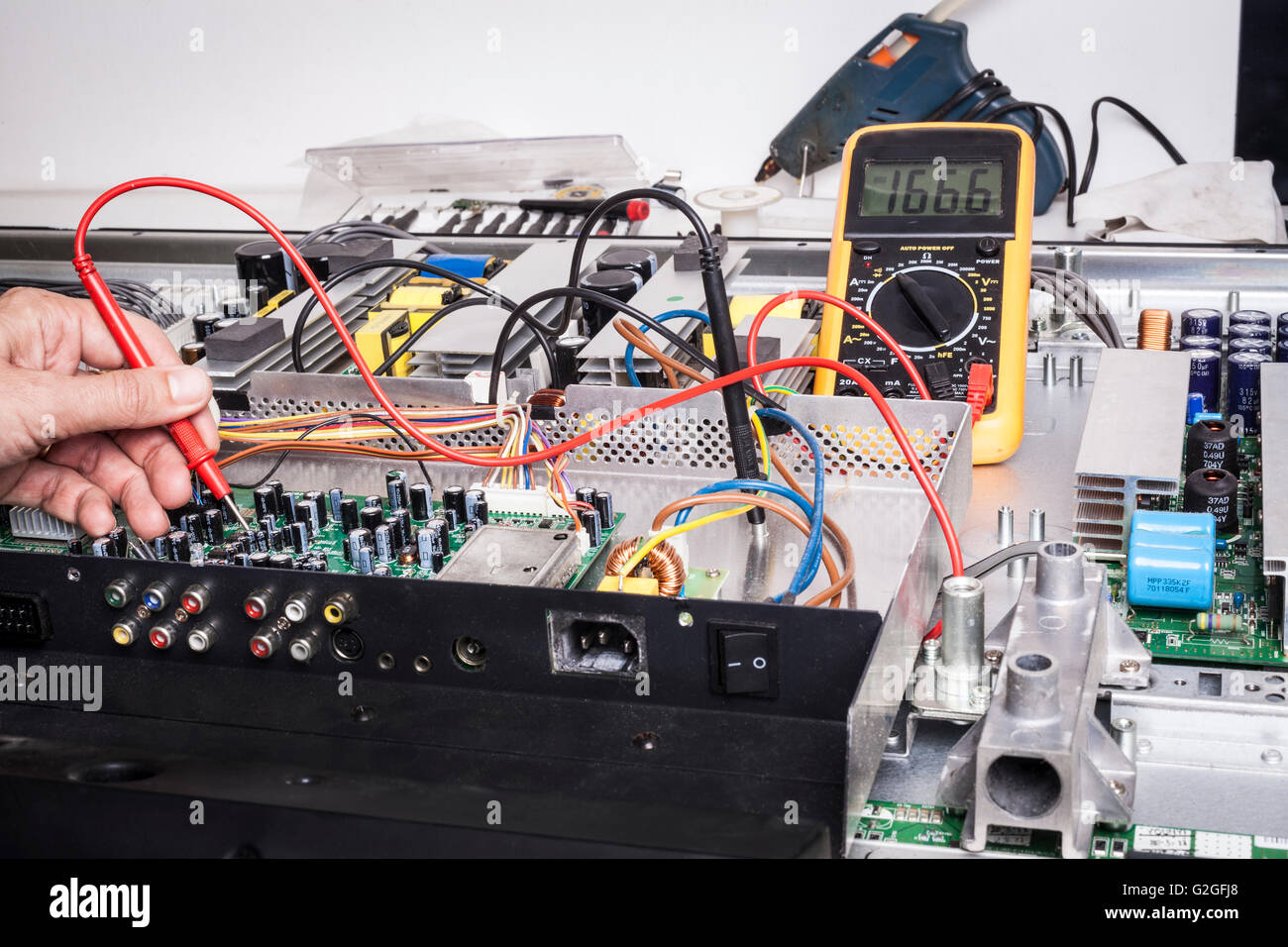 Elettronica per il servizio di riparazione con la sonda rossa e condensatori sulla scheda elettronica Foto Stock
