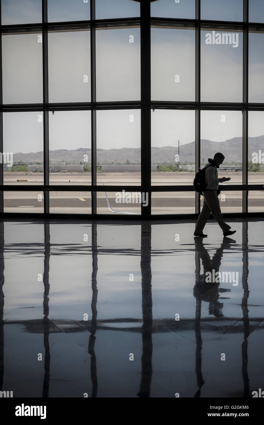 Uomo che cammina attraverso il terminal aeroportuale Foto Stock