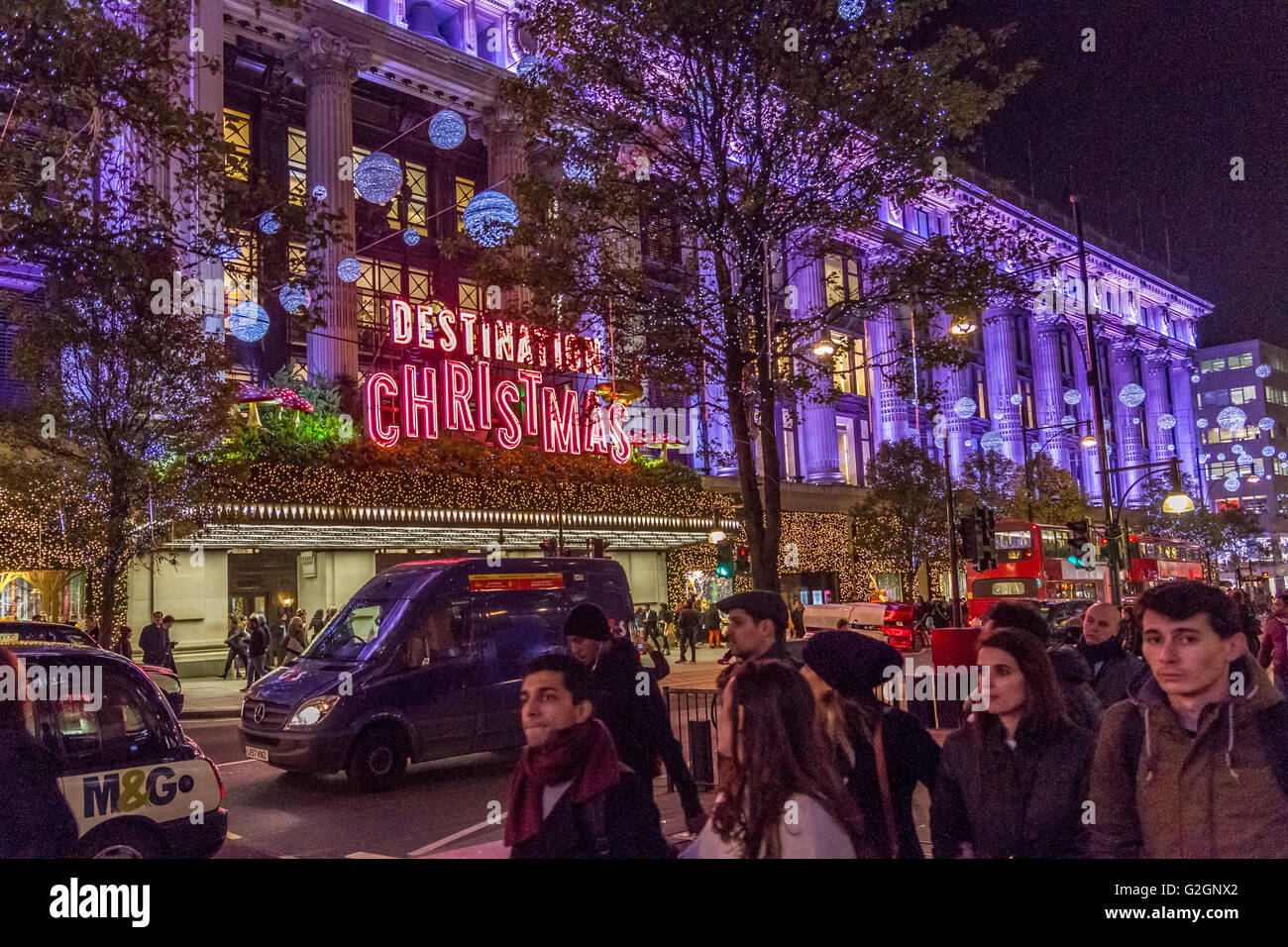 Gli amanti dello shopping natalizio su Oxford Street di Londra passano accanto al grande magazzino Selfridges, Londra, Regno Unito Foto Stock