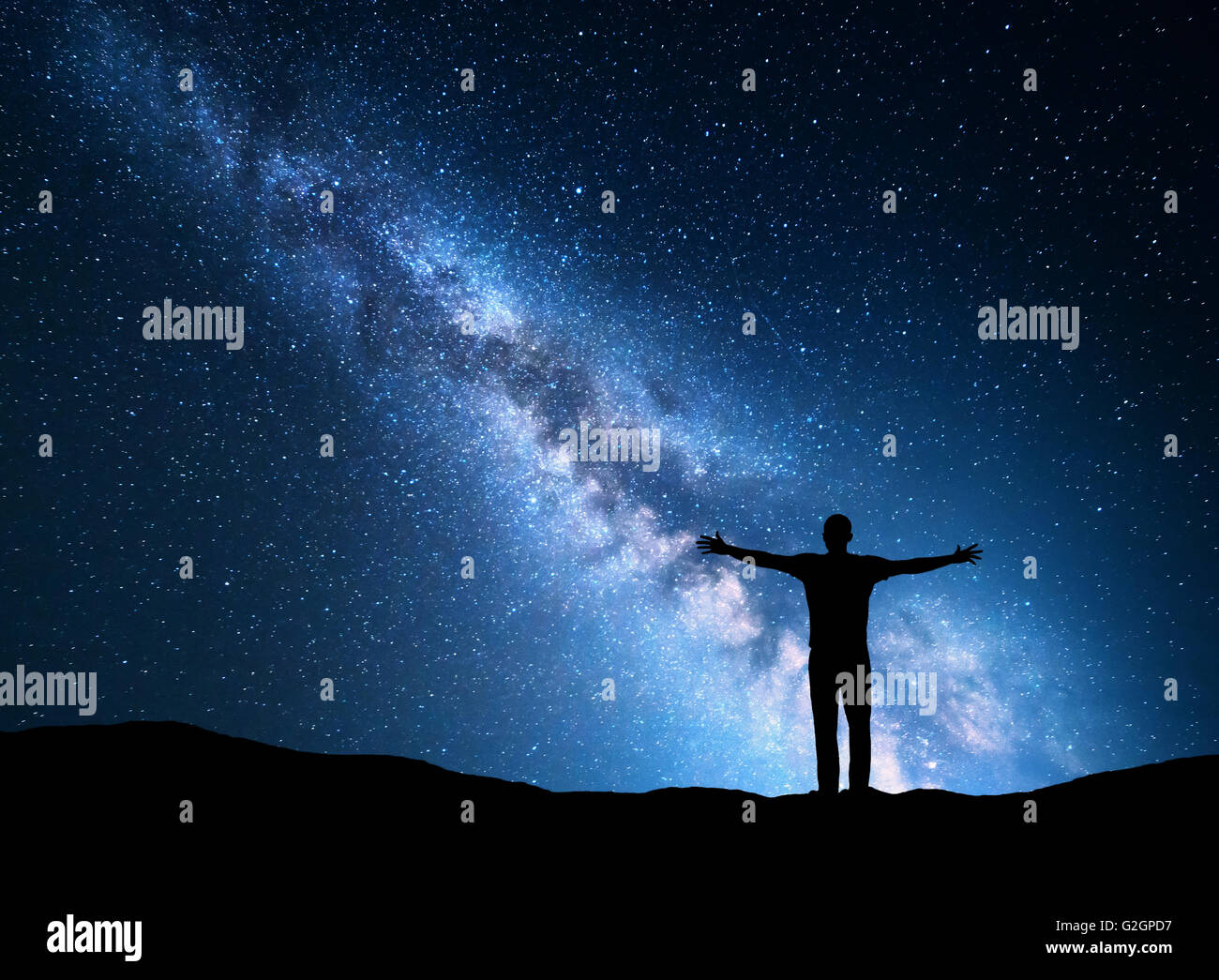 Notte paesaggio colorato con Via Lattea, blu luci della città e la silhouette di un permanente uomo sportivo con sollevate le armi Foto Stock