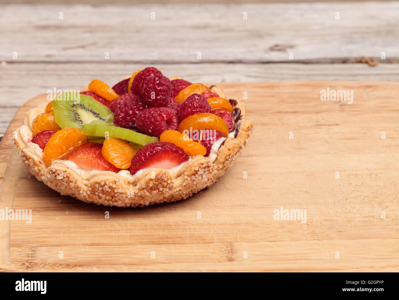 Crostata di frutta con un giallo crema pasticcera, ladyfinger cookie crosta shell, lamponi, fragole, kiwi e mandarini arance su un Foto Stock