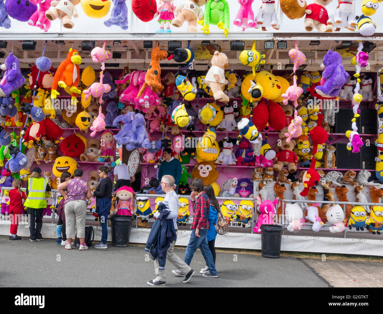Le persone che giocano alla fiera di stallo con ampia selezione di morbido peluche come premi Foto Stock