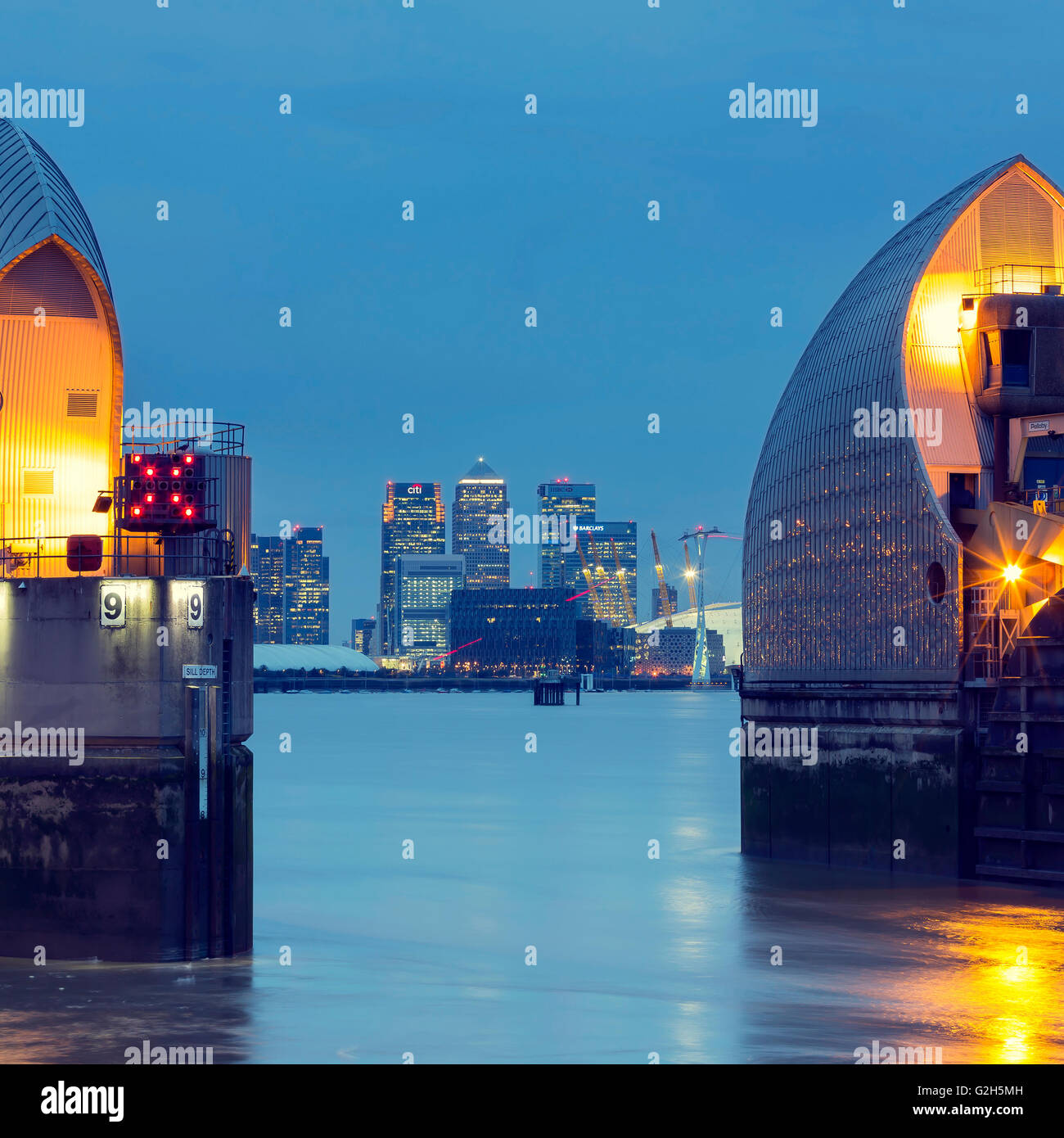 Thames Barrier, Millennium Dome e da Canary Wharf skyline con il landmark corporate edifici per uffici di notte Foto Stock