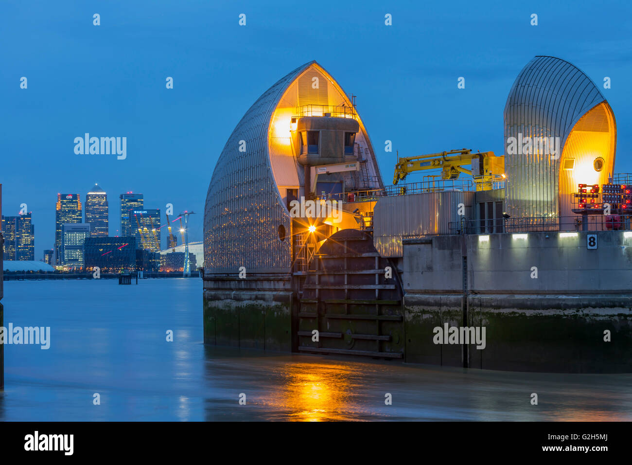 Thames Barrier, Millennium Dome e da Canary Wharf skyline con il landmark corporate edifici per uffici di notte Foto Stock