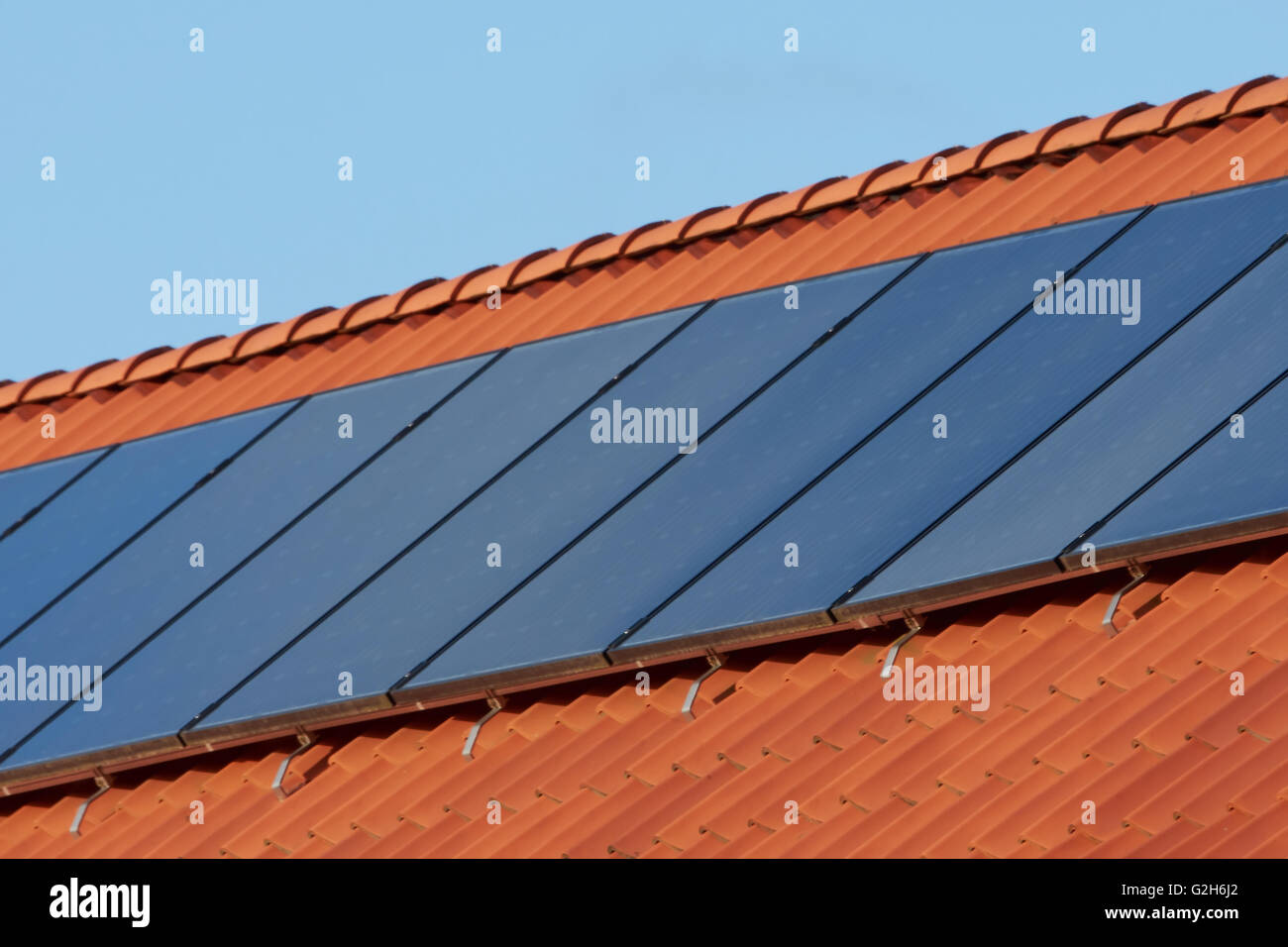Piatto piatto collettori solari termici su un rosso tetto di tegole Foto Stock