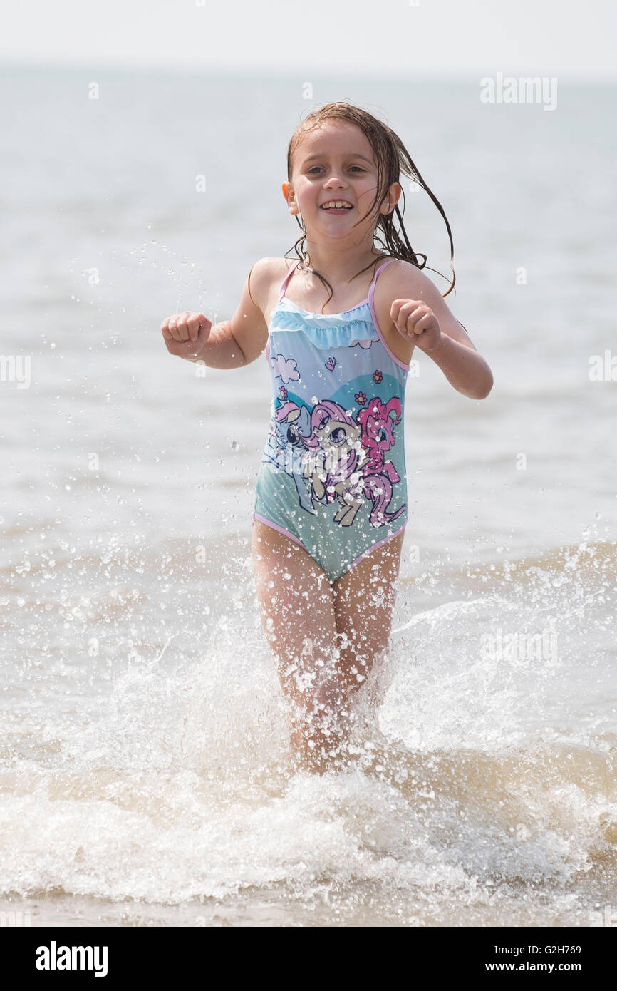 Una bambina gioca, schizzi e non si raffredda in mare durante le calde giornate di sole a Whitmore Bay, Barry Wales. Foto Stock