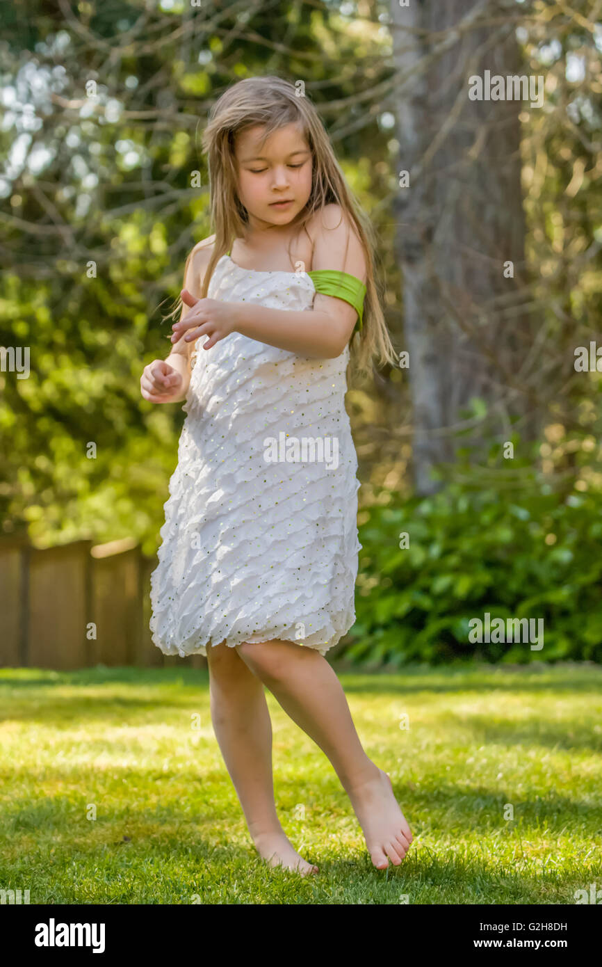 7 anno vecchia ragazza timidamente in ballo nel suo cortile in Issaquah, Washington, Stati Uniti d'America Foto Stock